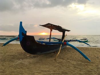 Deck chairs on beach against sky during sunset