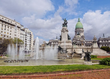 Fountain in city against sky