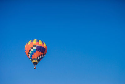 Low angle view of hot air balloon flying against clear blue sky