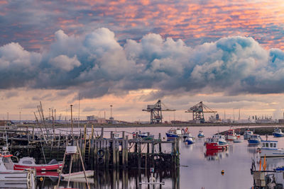 Sailboats moored at harbor during sunset