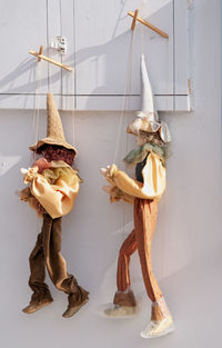 Two traditional greek handicraft puppets hanging on a wall in the village of oia in greece