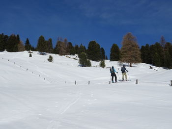 People skiing on snow covered mountain against sky