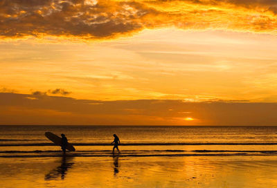 Silhouette people on beach against sky during sunset in kuta beach, bali