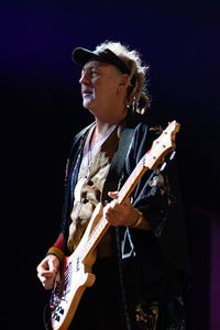 Young man playing guitar against black background