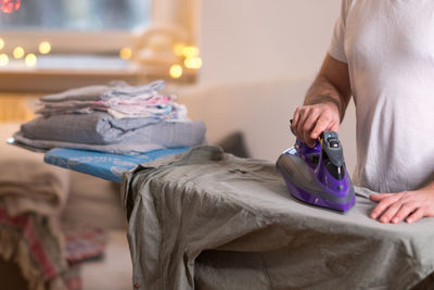 Midsection of man ironing shirt on board