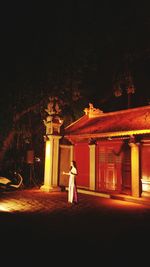 Woman walking on illuminated building at night