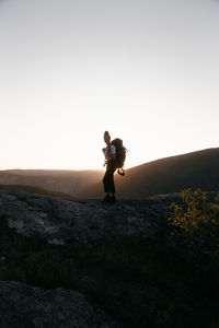 Rear view of woman walking on field against clear sky