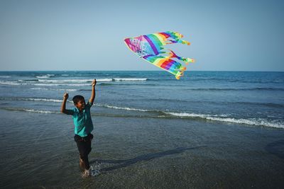 Boy playing in sea against clear sky