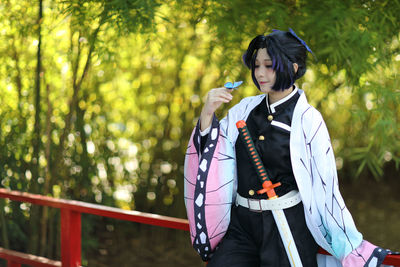 Side view of young woman standing in forest