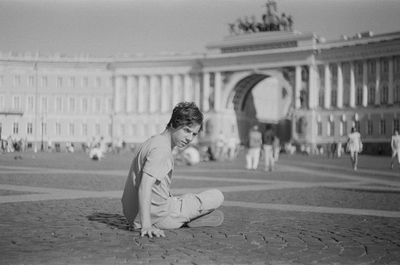 Young man sitting at dvortsovaya square in st. petersburg 