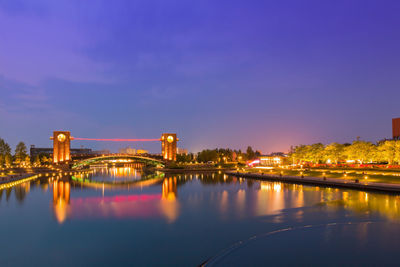 Illuminated bridge over river against sky at night