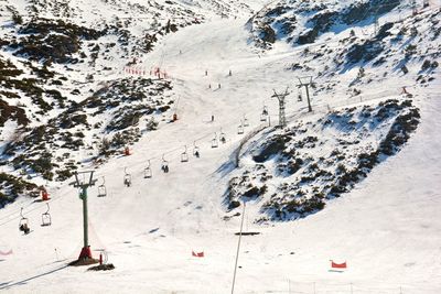 People in a ski lift skiing at a ski resort with mountains full of snow