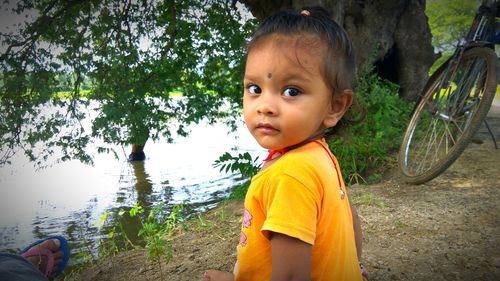 Portrait of boy standing by tree