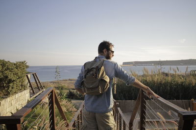 Rear view of man standing against clear sky