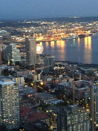 High angle view of illuminated cityscape by sea against sky