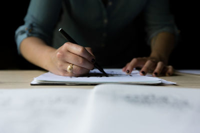 Cropped image of woman drawing on paper at table