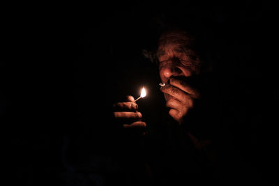 Man holding lit candle in darkroom