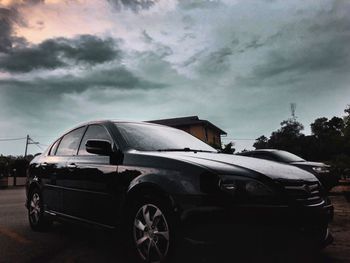 Vintage car on road against cloudy sky