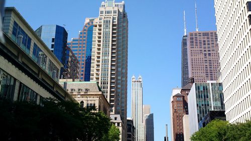 Directly below shot of modern buildings against clear sky