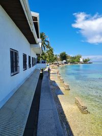 Footpath by building against blue sky