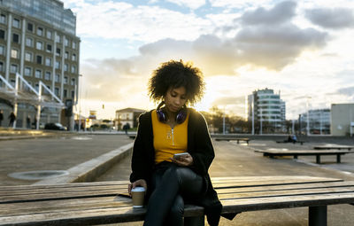 Man sitting in city against sky