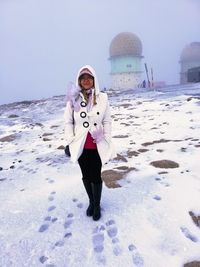 Full length portrait of young woman standing in snow