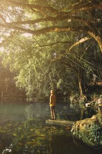 Full length of man standing by lake in forest