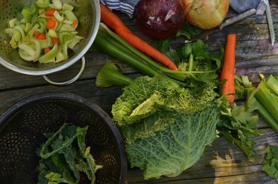 Overhead view of savoy cabbage, celery, carrots, collanders