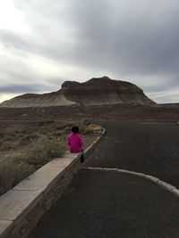 Rear view of woman walking on mountain against sky