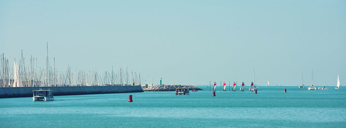 Boats in sea against clear sky