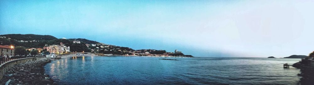 Scenic view of sea by city buildings against sky