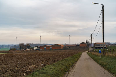 Street amidst field against sky