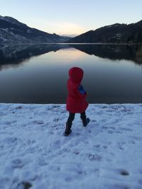 Rear view of boy walking in lake during winter