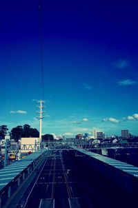 Railroad tracks in city against blue sky