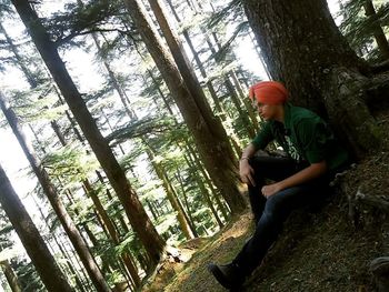 Side view of young woman sitting on tree trunk