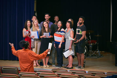 Teacher directing choir on stage in language school