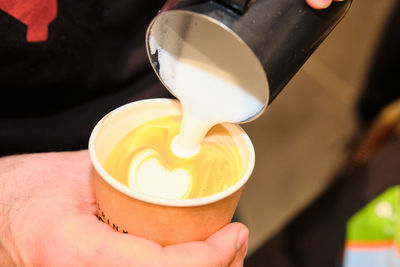 Cropped image of hand pouring coffee cup