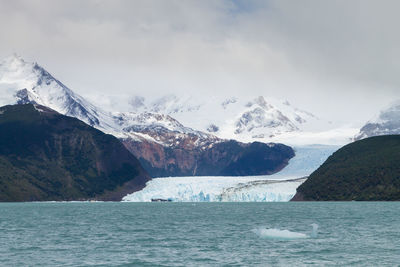 Scenic view of sea and snowcapped mountains against sky