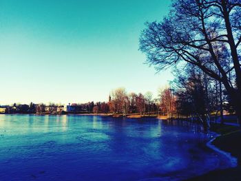 Swimming pool by lake against clear blue sky