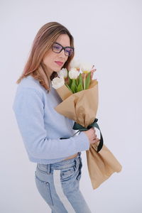 Midsection of woman with bouquet against white background
