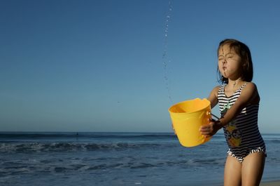 Full length of girl standing on beach against sky