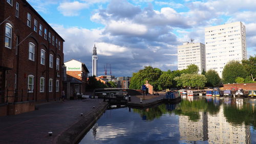 Canal amidst buildings in city against sky