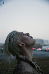 Side view of young woman against clear sky