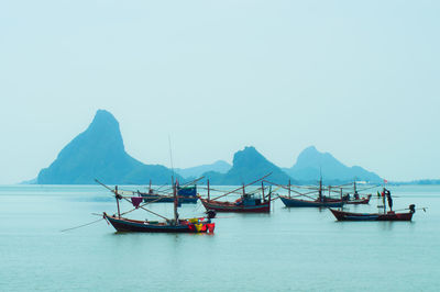 Fishing boats in sea against clear sky