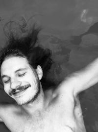 Smiling young man with eyes closed floating on water