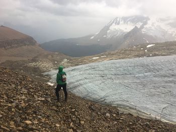 Rear view of man walking on mountain against sky