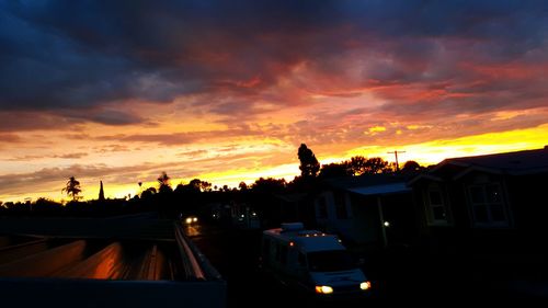 Silhouette of train against cloudy sky at sunset