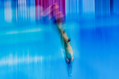 Blurred motion of shirtless man diving into swimming pool