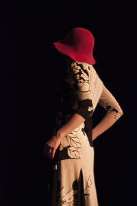 Woman wearing red hat while standing against black background