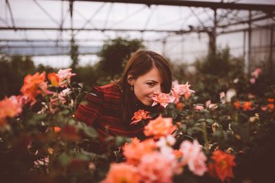 Portrait of woman with red flowers in greenhouse